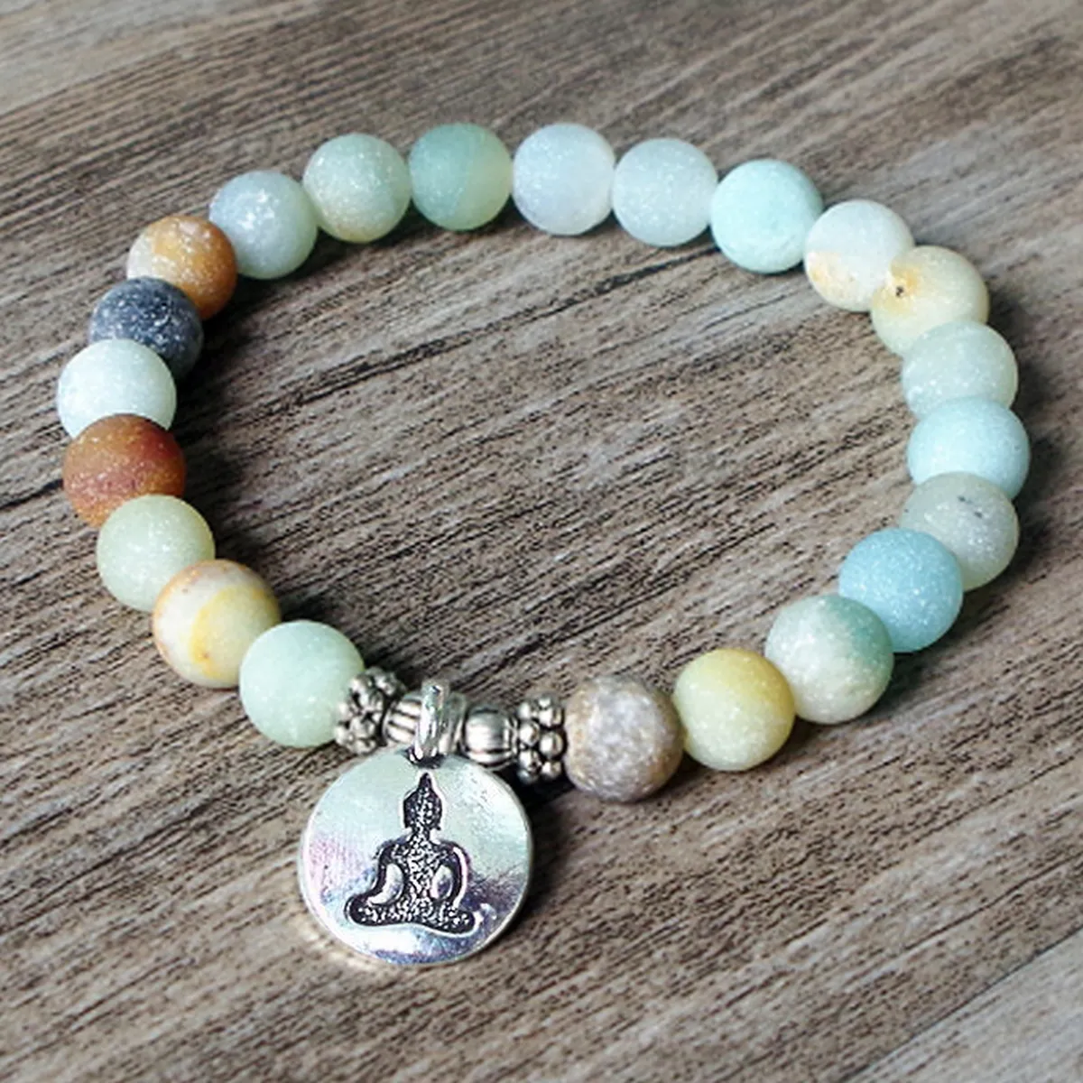 Amazonite bead bracelet with Buddha charm on a wooden board