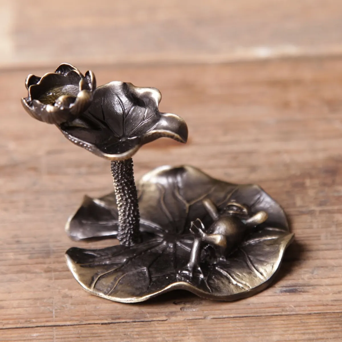 Small brass-finish lotus incense burner on a wooden table