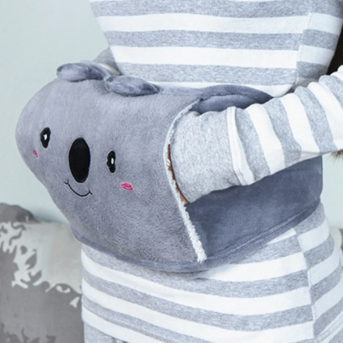 Grey fleece hot water bottle belt with koala design, hands tucked in the pocket
