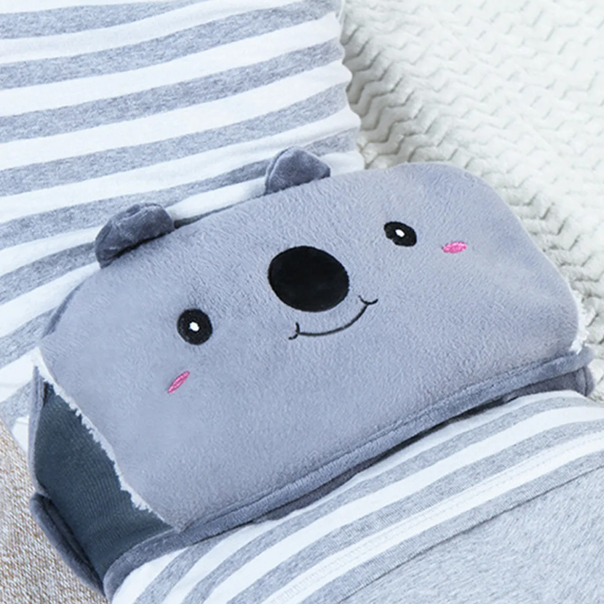 The koala hot water bottle belt worn over a striped jumper on the sofa