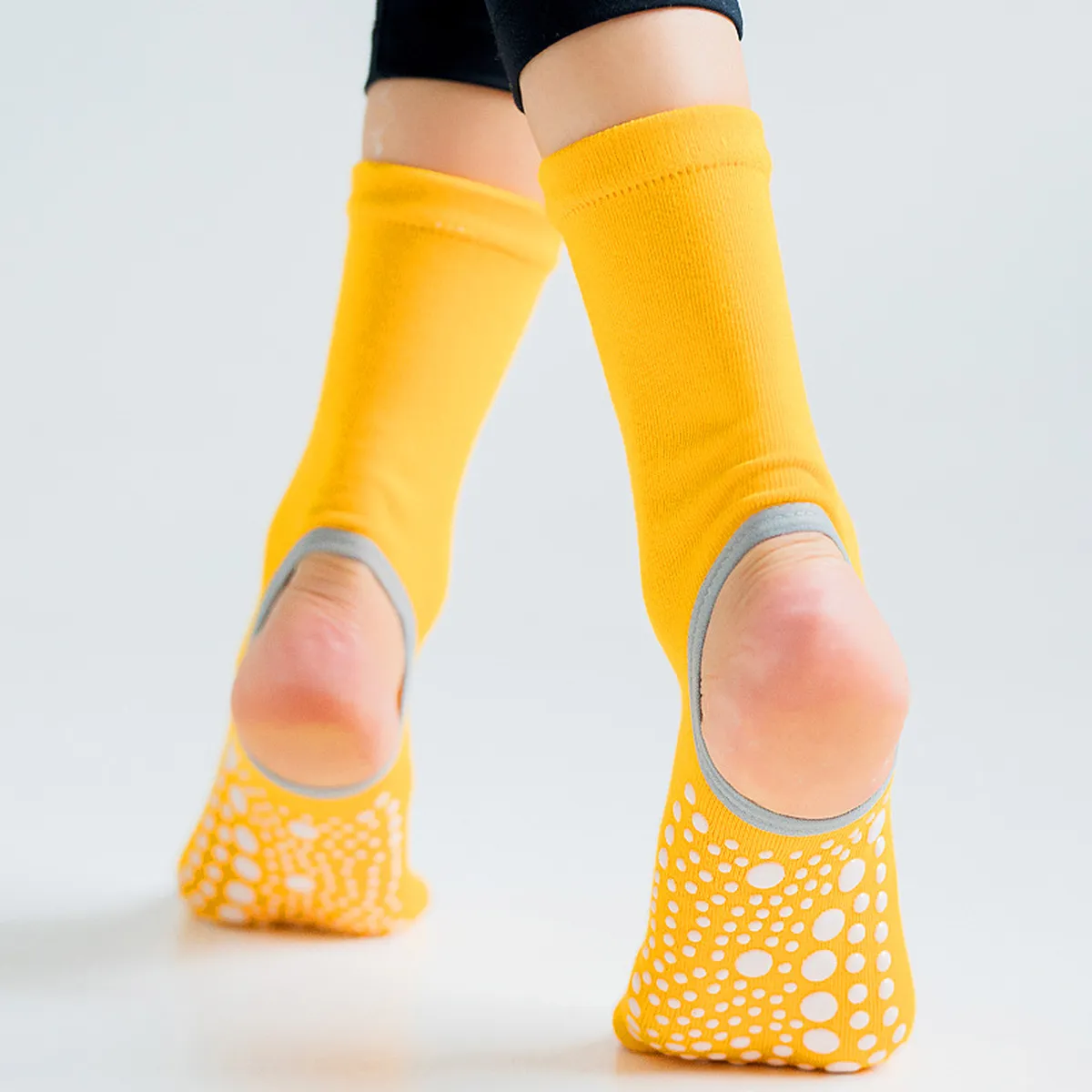 Yellow yoga socks worn, showing the non-slip dotted sole