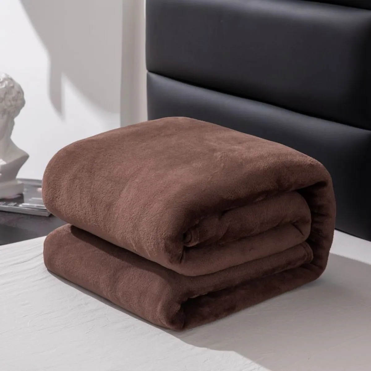 Brown fleece blanket folded on a bed
