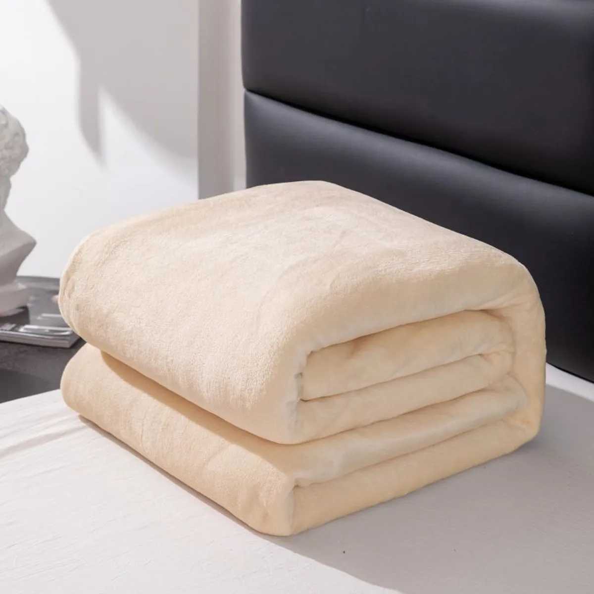 Beige fleece blanket folded on a bed