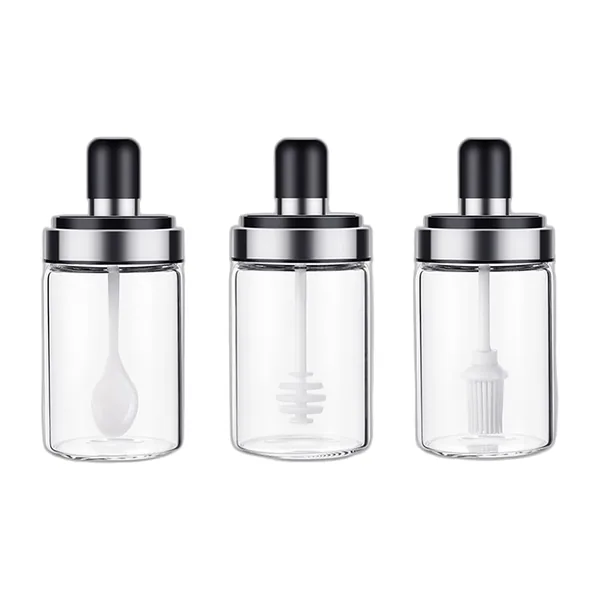 Three glass jars with black lids: spoon, honey dipper and brush