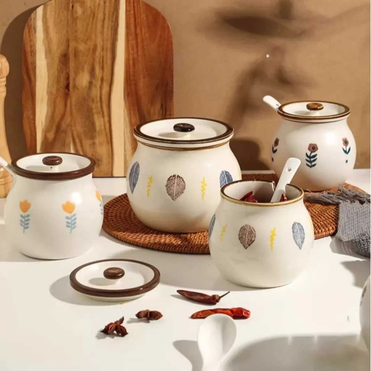 Leaf-painted ceramic jars on a kitchen table, with spoons