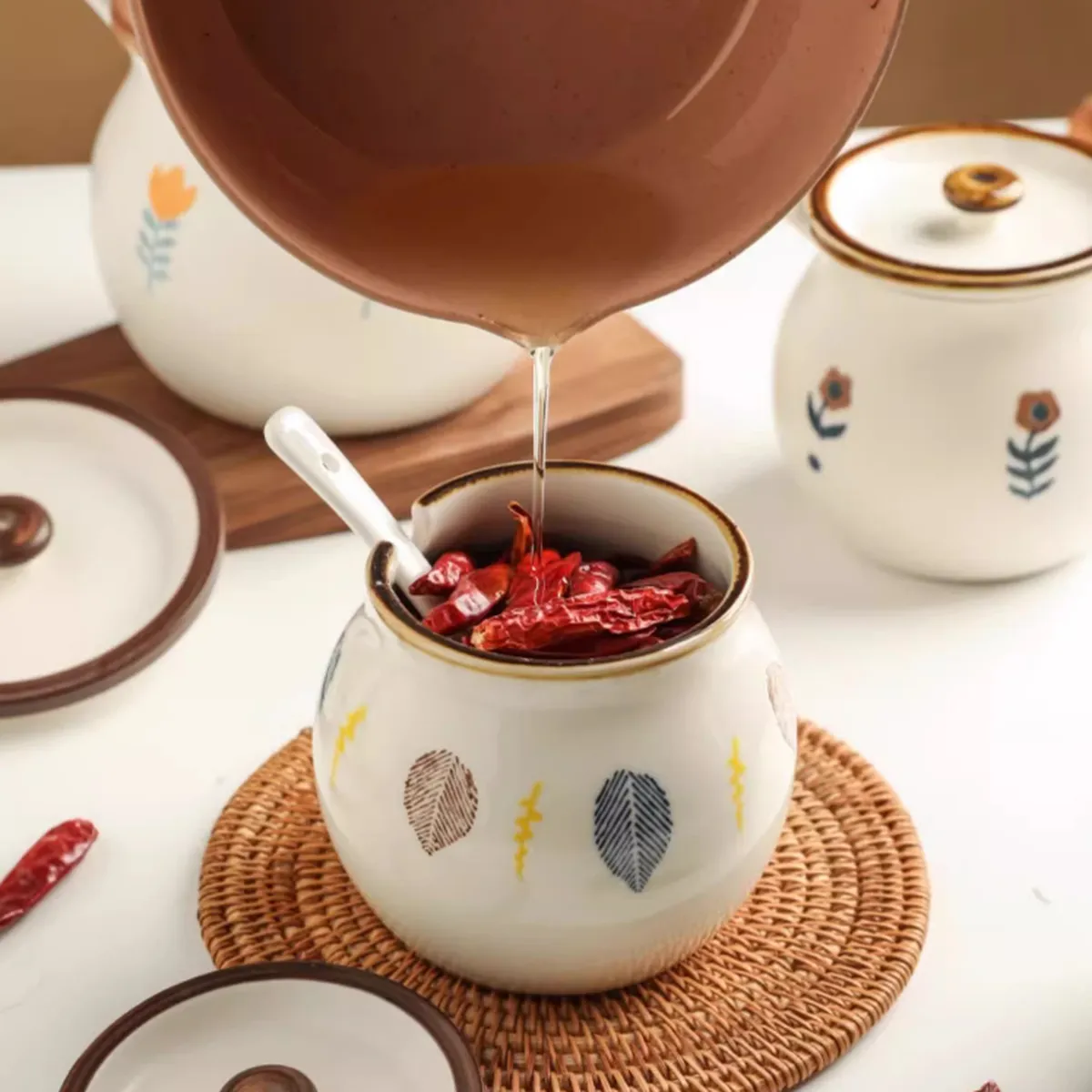 Leaf-painted ceramic jar filled with chillies on a rush trivet