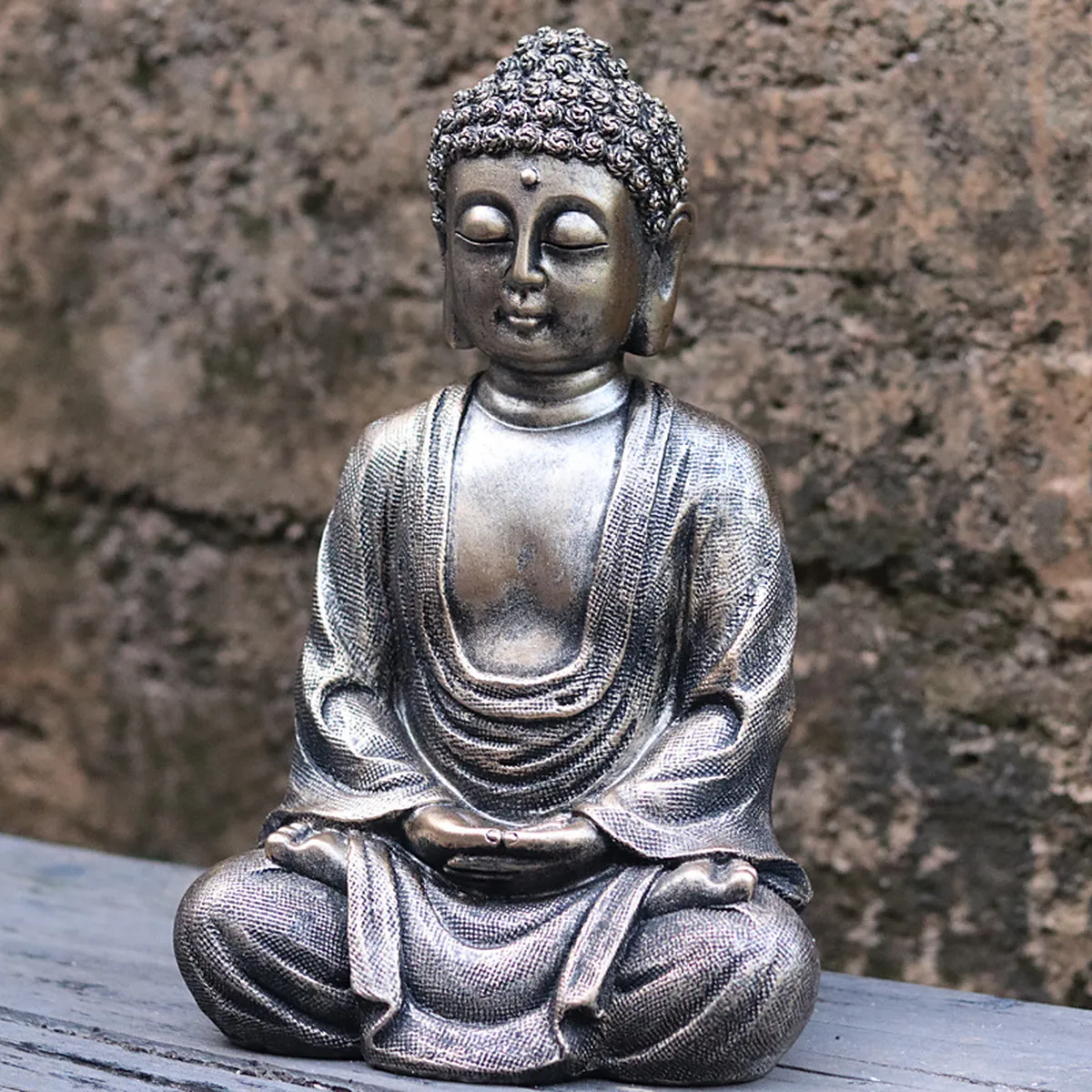 Bronze-effect Buddha figurine on a low stone wall