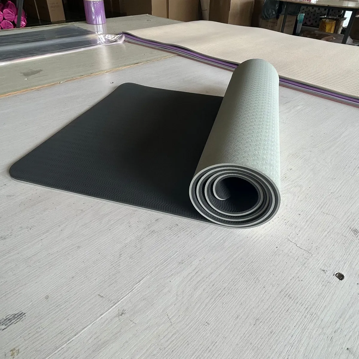 Grey and black two-tone yoga mat half unrolled on a table
