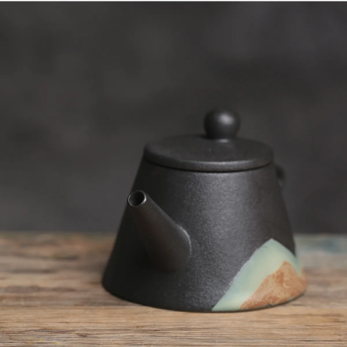 Matte ceramic teapot with mountain decor on a wooden table